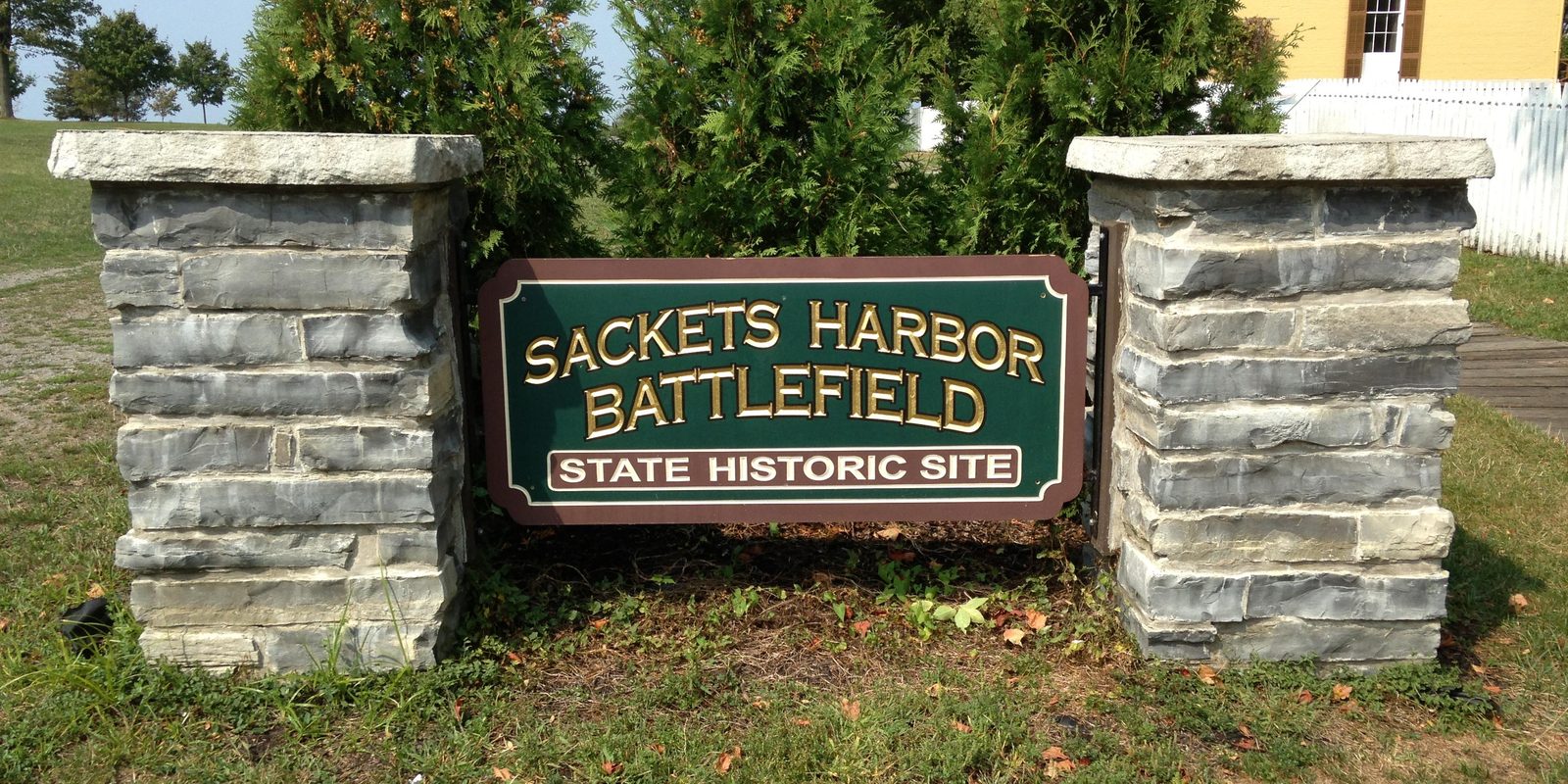 The Sackets Harbor Battlefield State Historic Site sign between two stone pillars