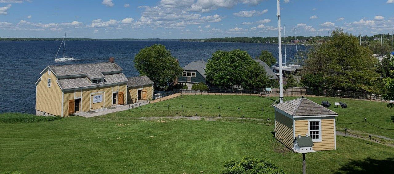 The Sackets Harbor Battlefield grounds above the harbor, with the Navy Yard buildings and sailboats on the lake