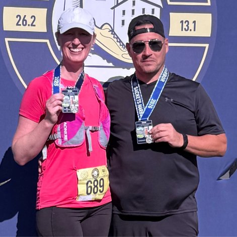 Two finishers showing off their medals at the finish